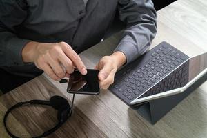 vista superior da mão do homem usando fone de ouvido voip com teclado de encaixe de computador tablet digital, telefone inteligente, comunicação de conceito, suporte, call center e atendimento ao cliente help desk na mesa de madeira foto