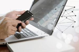 mão de empresário usando laptop e celular no escritório foto