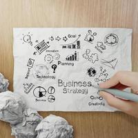 mão desenhando estratégia de negócios criativa em papel amassado com fundo woden como conceito foto