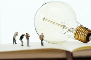 conceito de ideia criativa - fotógrafo em miniatura com lâmpada vintage no caderno de papel aberto foto
