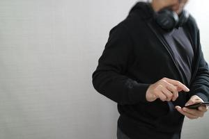 homem encapuzado hipster com fones de ouvido ouvindo música com telefone inteligente pagamento móvel compras on-line, rede social, vista frontal foto