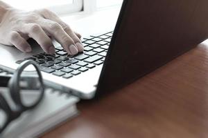 close-up do homem de negócios trabalhando no computador portátil na mesa de madeira como conceito foto