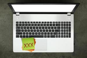 xxx na nota syicky com computador portátil de tela em branco no fundo da mesa de textura foto