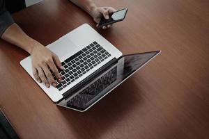 vista superior da mão do empresário trabalhando com novo computador moderno e telefone inteligente e estratégia de negócios na mesa de madeira como conceito foto