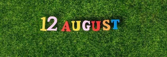12 de agosto. imagem de letras coloridas de madeira e números em 12 de agosto no contexto de um gramado verde. foto