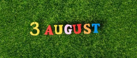 3 de agosto. imagem de letras coloridas de madeira e números em 3 de agosto no fundo de um gramado verde. um dia de verão. foto