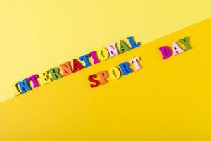 letras de madeira dia internacional do esporte em um fundo amarelo. foto