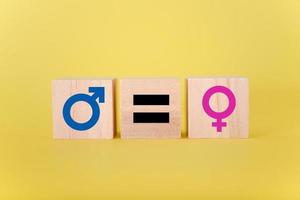 símbolos de ícone masculino e feminino em blocos de madeira contra um fundo amarelo. foto
