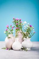 vasos com lindas flores na mesa de luz foto