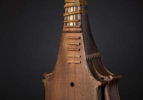 parte instrumento musical de cordas asiático antigo em fundo preto com luz de fundo foto