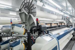 máquinas e equipamentos na tecelagem. interior da fábrica têxtil industrial foto