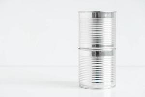 duas latas de metal fechadas de alumínio em uma mesa branca. copiar, espaço vazio para texto foto