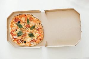 pizza em uma caixa de papelão em um fundo de mesa branca. vista do topo. copiar, espaço vazio para texto foto