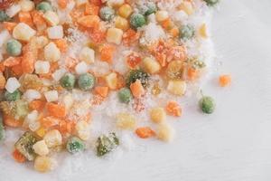 mistura de legumes congelados em fundo branco foto