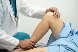 Médico fisioterapeuta examinando, massageando e tratando o joelho e a perna do paciente sênior no hospital de enfermagem da clínica médica ortopedista.