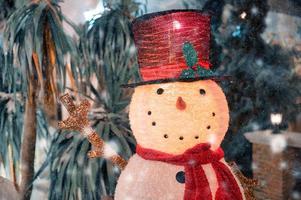 boneco de neve com chapéu e cachecol em queda de neve no festival de natal foto