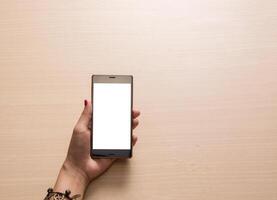 smartphone na mão, close-up no fundo de madeira foto