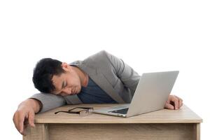 empresário dormindo ao lado de seu computador portátil com fundo branco. foto