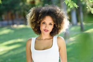 jovem negra com penteado afro sorrindo no parque urbano foto