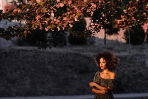 jovem negra com penteado afro sorrindo em meio urbano foto