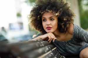 jovem negra com penteado afro sorrindo em meio urbano foto