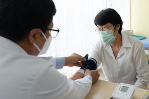médico mede a pressão arterial do paciente sênior foto