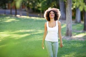 jovem negra com penteado afro sorrindo no parque urbano foto