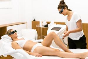 mulher recebendo depilação a laser de pernas em um centro de beleza. foto
