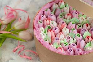 marshmallows artesanais em embalagens de madeira sobre um fundo claro com flores. o conceito de feriados do dia da mulher e dia dos namorados. foto