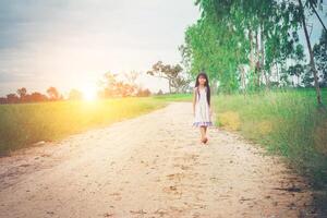 menina com vestido de cabelo comprido está se afastando de você na estrada rural. foto