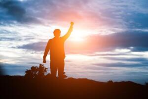 homem de braços levantados contra o belo pôr do sol. foto