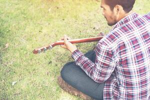 homem jovem hippie praticou guitarra no parque, feliz e gosta de tocar guitarra. foto