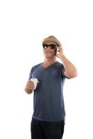 jovem bonito hipster de chapéu e óculos de sol em pé e falando no celular sobre fundo branco. foto