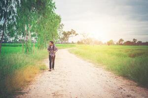 homem jovem hippie com mochila no ombro andando pela zona rural. foto