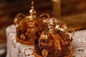coroas de ouro do casamento em cima da mesa na igreja. coroas de casamento na igreja prontas para a cerimônia de casamento. fechar-se. liturgia divina. foto