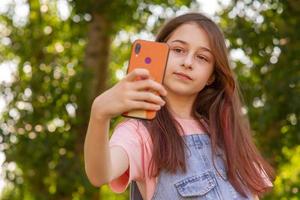 uma adolescente tira uma selfie no telefone. smartphone nas mãos de uma garota. foto