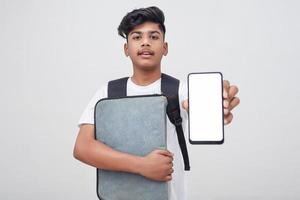 jovem estudante indiano segurando o arquivo e mostrando a tela do smartphone em fundo branco. foto