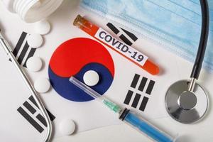 coronavírus, o conceito covid-19. vista superior máscara de respiração protetora, estetoscópio, seringa, pílulas na bandeira da coreia do sul. foto