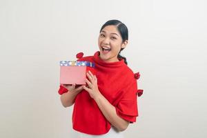 Mulher asiática feliz vestindo uma camisa vermelha com uma caixa de presente disponível para o festival de Natal foto