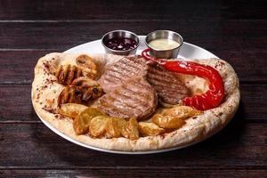 delicioso bife de frango suculento com batatas assadas, cogumelos e molhos foto