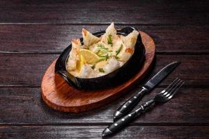 um delicioso prato de frutos do mar assado com queijo e pão ralado em uma tigela de ferro fundido foto