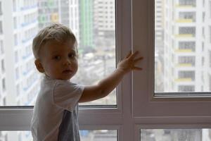 lindo menino com rosto de criança posando para fotógrafo perto da janela foto