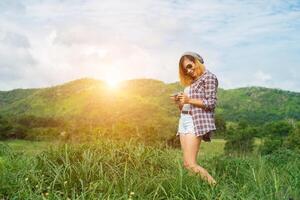 mulher jovem hippie com câmera retrô, tirando um tiro na paisagem ao ar livre, natureza de montanha de estilo de vida no fundo. foto