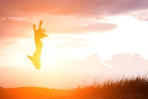 mulher feliz pulando contra o belo pôr do sol foto