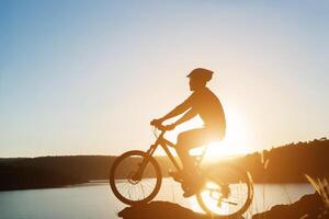 silhueta de um homem em mountain bike durante o pôr do sol. foto