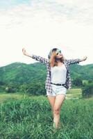 jovem e bela mulher desfrutando de liberdade e vida na natureza atrás da montanha. foto