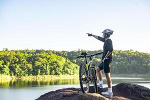 ciclistas de montanha ficam no topo da montanha com a bicicleta e apontam o dedo na frente. foto