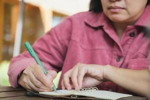 mulher escrevendo objetivo no notebook no espaço ao ar livre da cafeteria foto