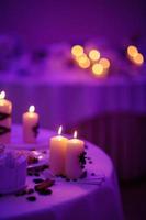 linda mesa decorada com enfeites de flores e velas vermelhas. noite de natal ou decoração de festa de casamento. foto