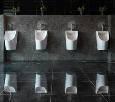 mictórios brancos cerâmicos no banheiro masculino foto